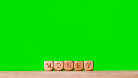 Business-Concept-Wooden-Letter-Cubes-Or-Dice-Spelling-Money-Against-Green-Screen